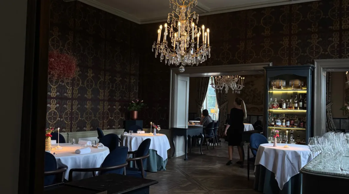 Elegant restaurantinterieur van Château Neercanne met kristallen kroonluchter en gedekte tafels