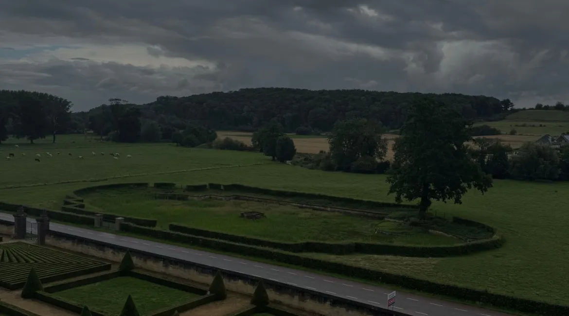 Uitzicht over de baroktuinen en het glooiende landschap van Limburg bij Château Neercanne