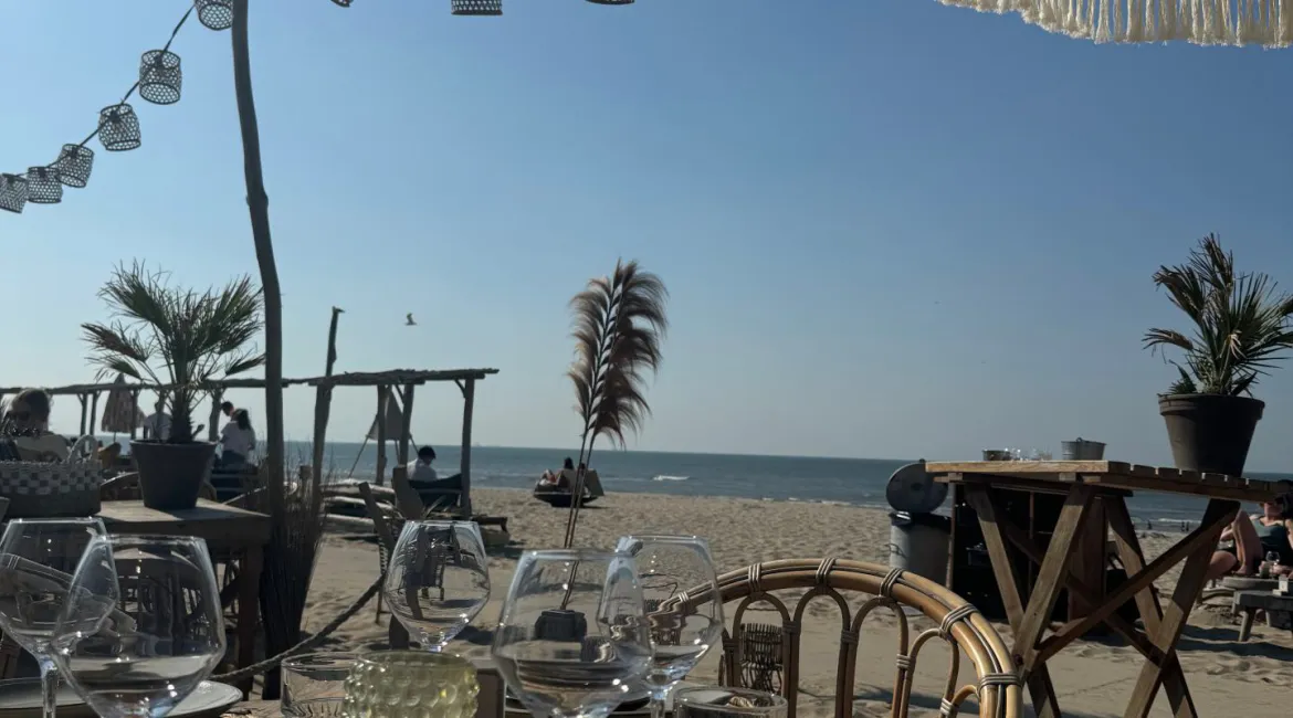 Terras van beachclub Tulum in Noordwijk met uitzicht op zee, bohemien parasols en zomerse tafelaankleding